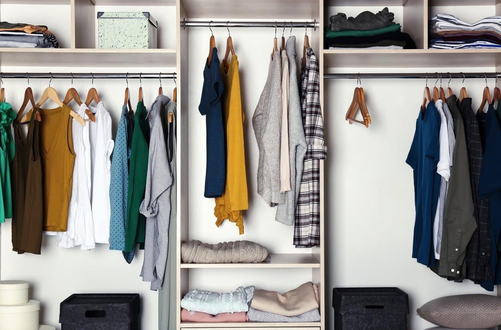 Open shelved closet with hangers and folded clothes inside