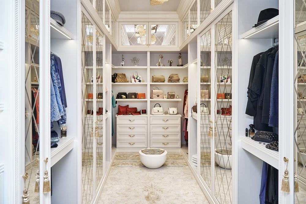 White custom closet with accessories and clothes inside