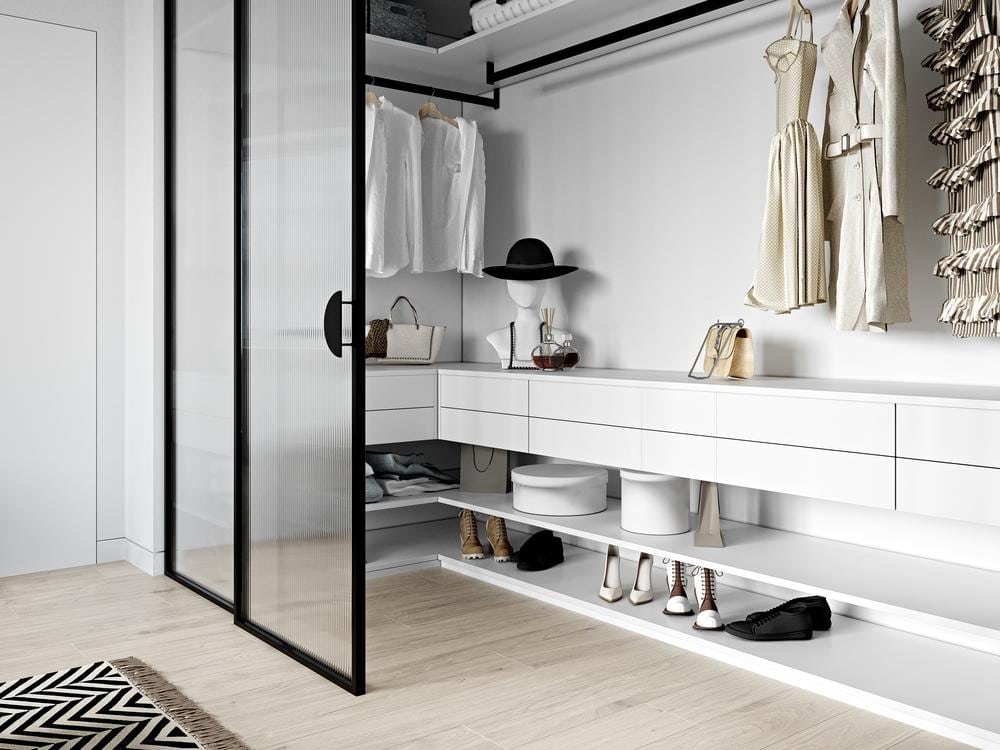Glass door reach in closets with small drawers and black clothing hangers