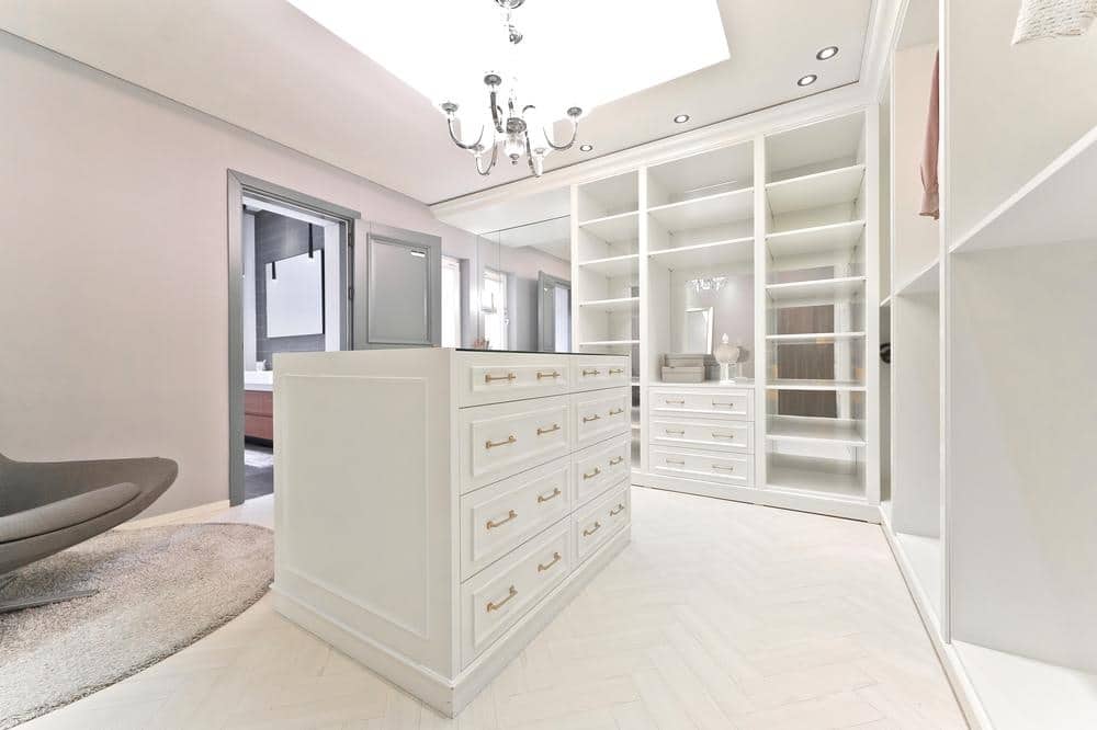 White walk in closet with empty sections in the closets and an island in the middle