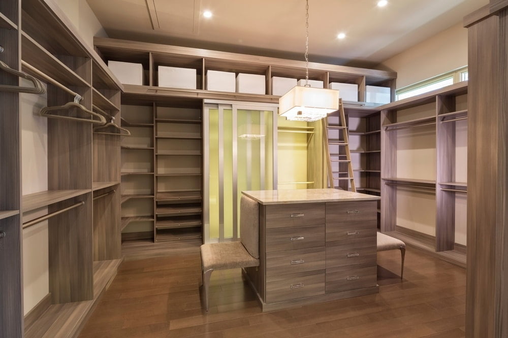 Empty wooden walk in closet with an island