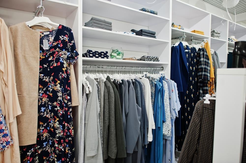 Colorful clothes inside of a white wardrobe with set racks