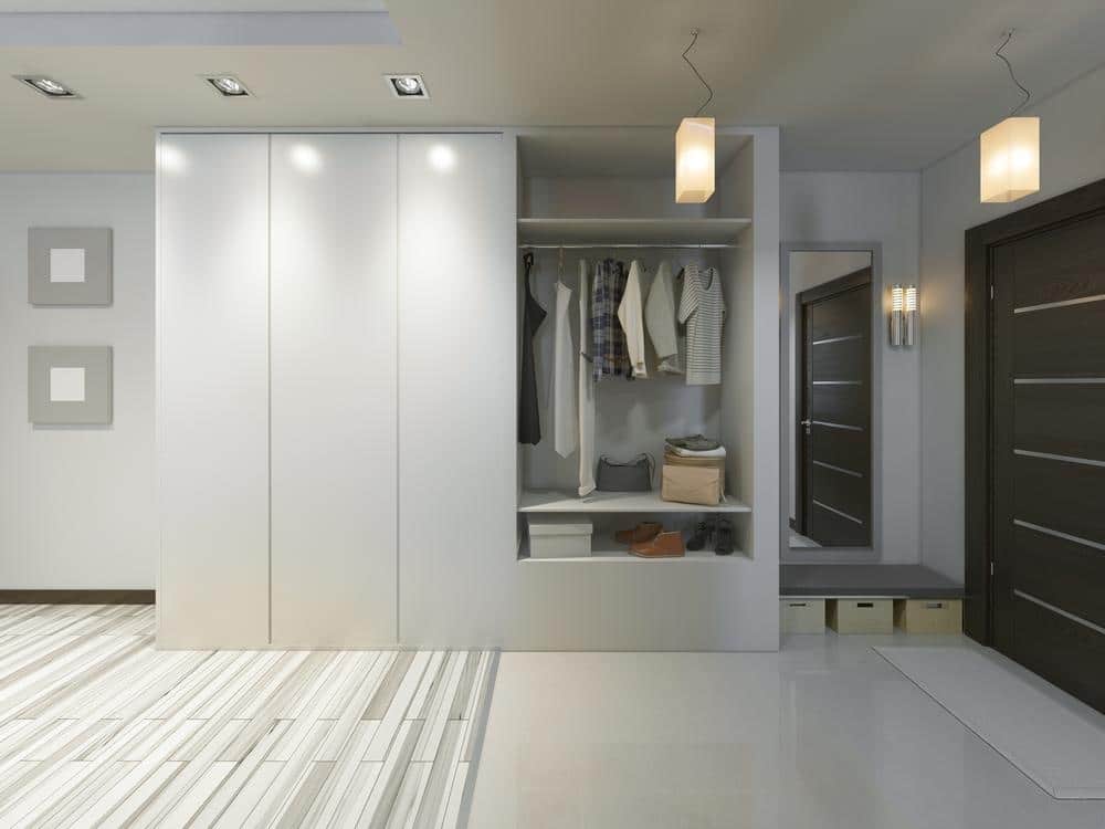 White entryway closet with hangers and closed doors