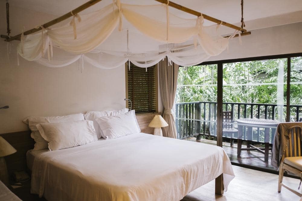 Simple bedroom with canopy bed and large windows that opens up to the balcony