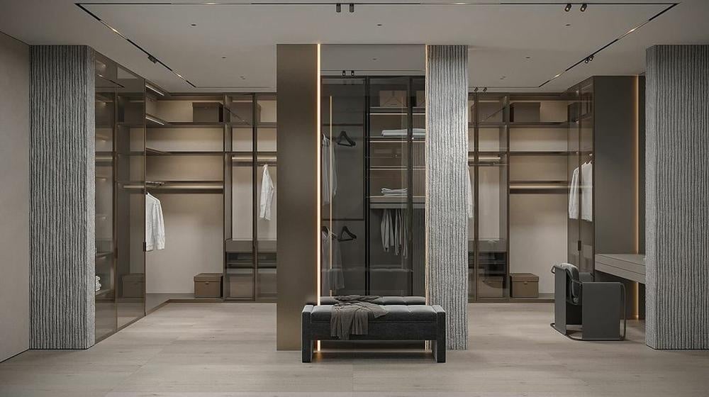 Large grey walk in closet with glass door panels and small bench