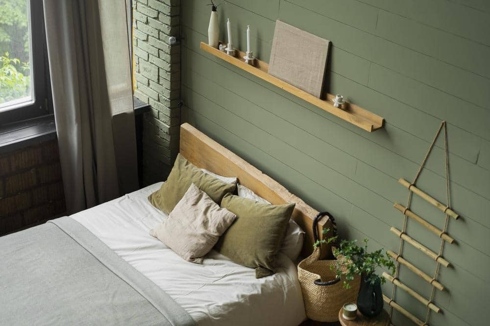 Green wall bedroom with a large bed and wall hung shelf above the bed
