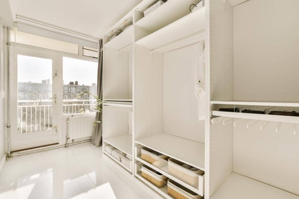 https://bienalclosets.com/wp-content/uploads/2023/10/inside-room-with-white-walls-shelves-each-side-there-is-open-door-that-leads-balcony.jpg