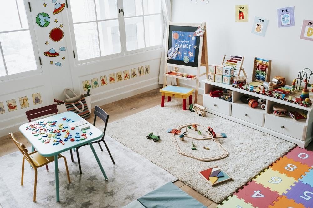 Craft room with toys scattered around the room and a white carpet