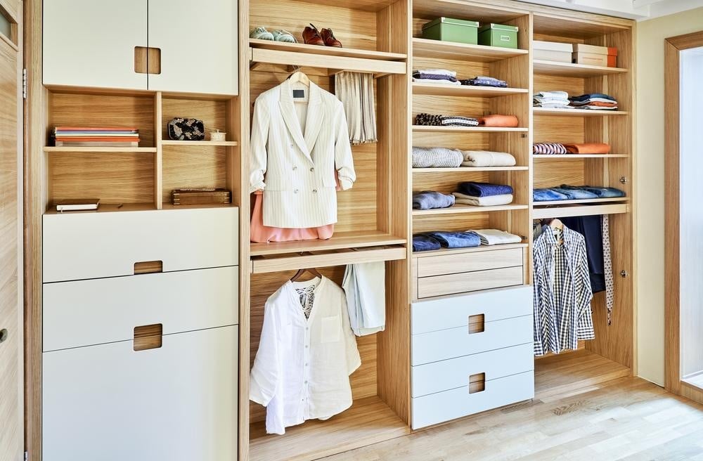 Light colored custom closet with hangers and white drawers
