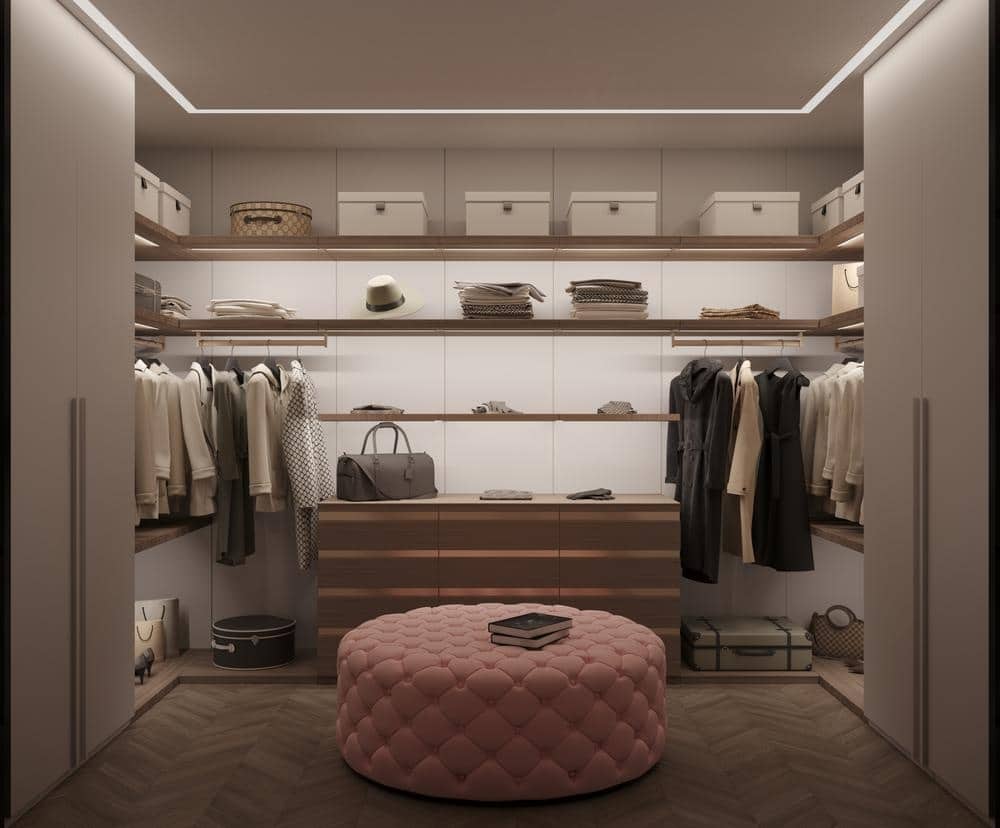Dim lighted custom closet with pink ottoman in the middle