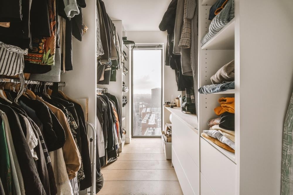Double sided walk in closet with hanged clothes inside