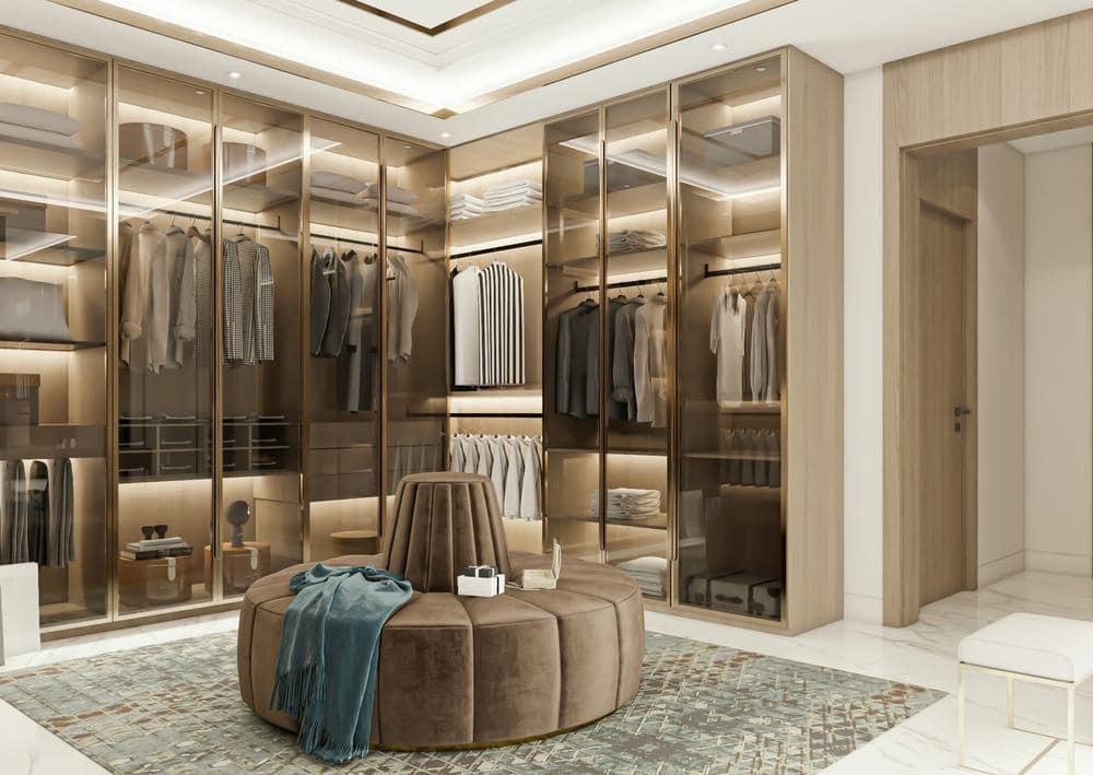 Luxury walk in closet with glass doors and led lights and a ottoman