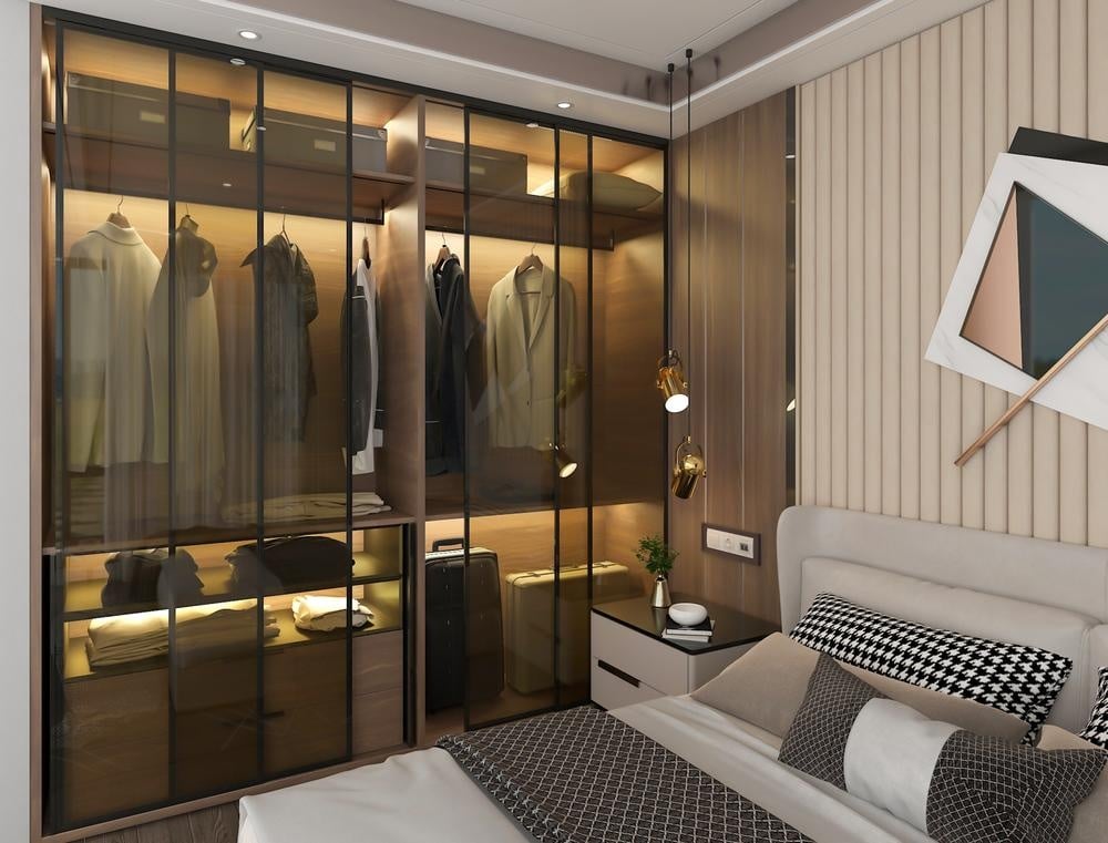 Luxury built in closet with glass doors next to a bed
